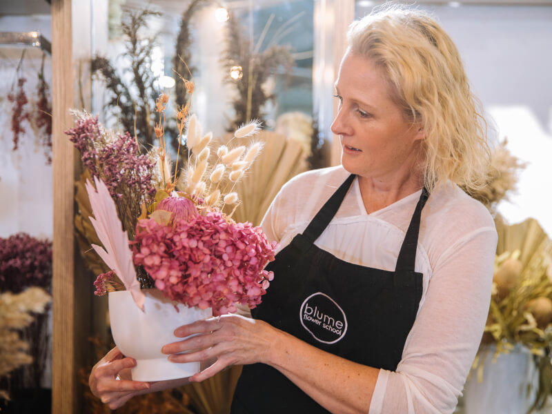 A woman looks at her dried flower arrangement.